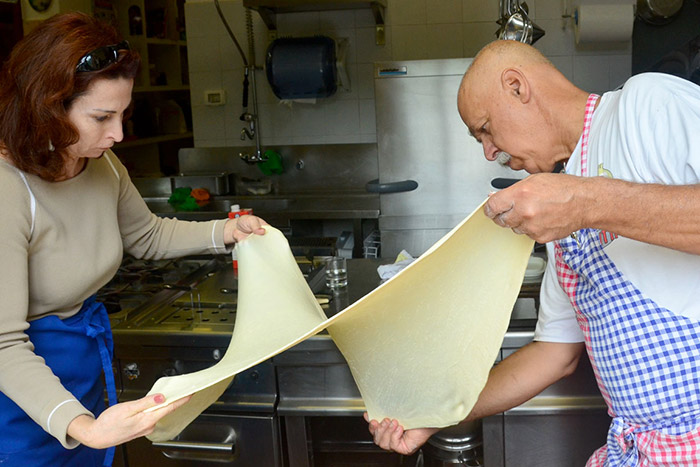 Cooks working a fresh sheet of pasta dough